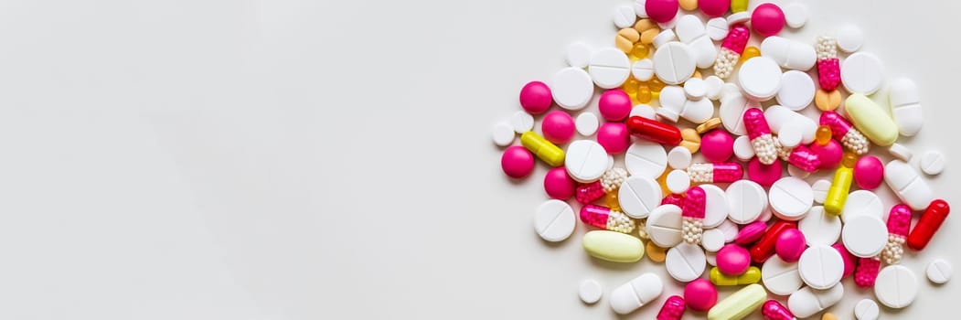 Pile of colorful medicine pills, white, blue, yellow and red, sitting on white background