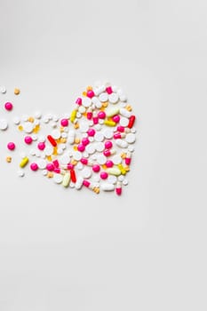 Pile of colorful medicine pills, white, blue, yellow and red, sitting on white background