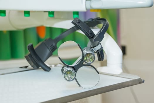 the dental binocular loupes on white tablel in dental office. Dentist goggles, protective glasses in dentist's office. Dentistry.
