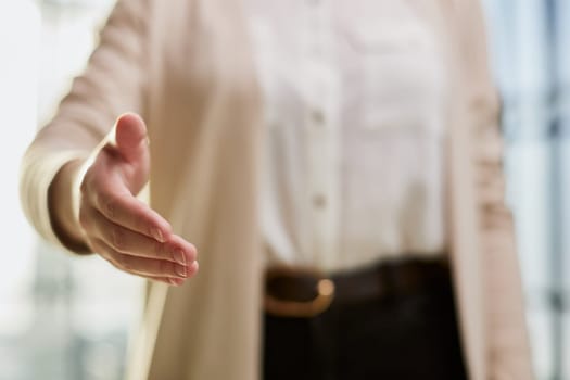 businesswoman proposes partnership, gives hand at camera for handshake