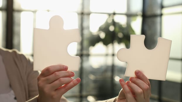 Business Woman holding two blank white puzzle pieces in his hands conceptual of solving a problem