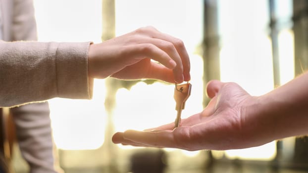 From hand to hand. Close up shot of hand of female seller owner of house apartment office holding keys giving it to young woman buyer renter after conclusion of successful deal and getting downpayment