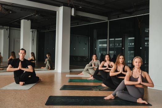 a group of girls do yoga in the gym under the guidance of a coach.