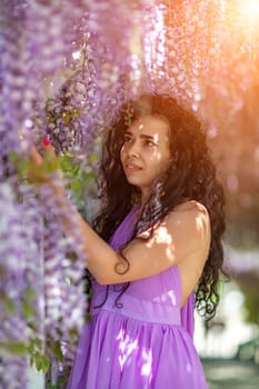 Woman wisteria lilac dress. Thoughtful happy mature woman in purple dress surrounded by chinese wisteria.