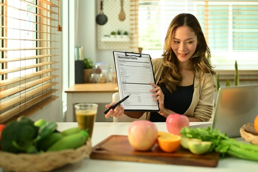 Attractive female nutritionist showing example of weekly menu during online consultations via laptop. Right nutrition, healthy eating.