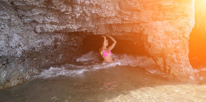 Woman travel sea. Young Happy woman in a long red dress posing on a beach near the sea on background of volcanic rocks, like in Iceland, sharing travel adventure journey