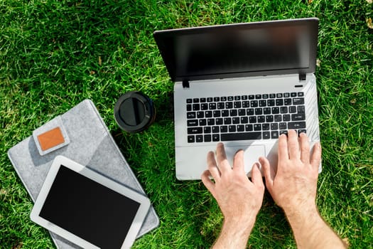 Close-up shot of handsome man's hands touching laptop computer's screen. Businessman using a laptop computer and sitting on the ground.