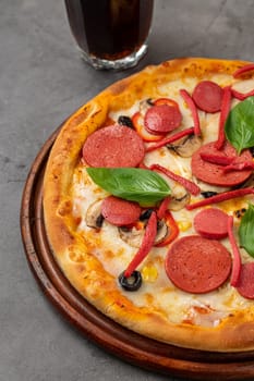 Mixed pizza with sausage, salami and mushrooms on a stone table
