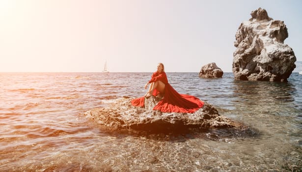 Woman travel sea. Young Happy woman in a long red dress posing on a beach near the sea on background of volcanic rocks, like in Iceland, sharing travel adventure journey