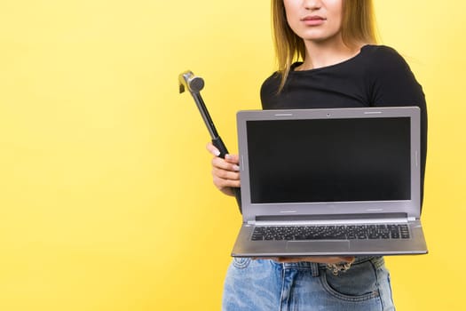 Laptop Repair. Female with hammer and laptop on a yellow background