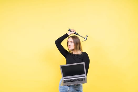 Laptop Repair. Female with hammer and laptop on a yellow background