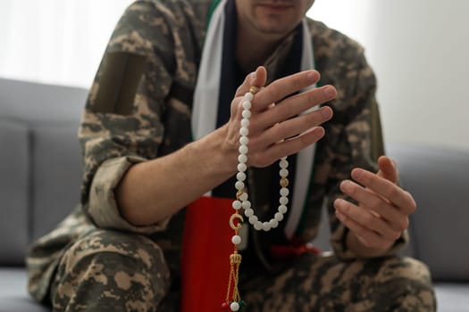 Soldier in camouflage with a rosary in her hands.