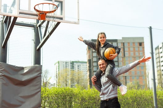 Happy father and teen daughter outside at basketball court