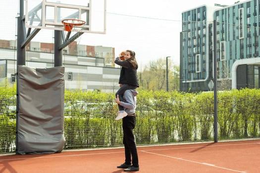 Happy father and teen daughter outside at basketball court