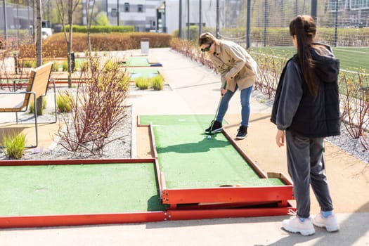 mother and daughter enjoying together playing mini golf in the city