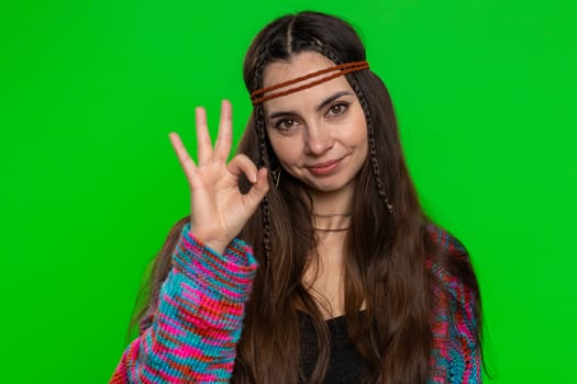 Okay. Young happy hippie woman looking approvingly at camera showing ok gesture, like sign positive, approve something good. Pretty girl isolated alone on studio chroma key background, green screen