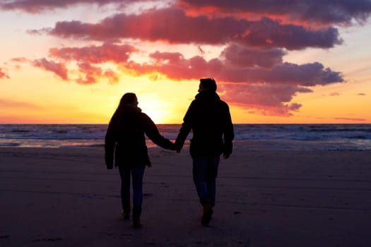 Beach, silhouette and couple holding hands at sunset while walking, bonding and enjoying freedom. Love, shadow and man with woman at the ocean for travel, romance and sunrise walk on Hawaii vacation.