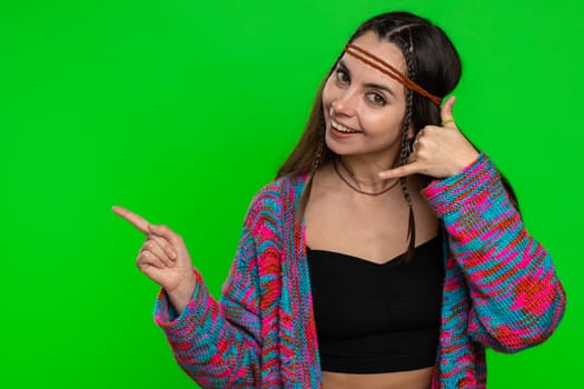 Call us, here is contact number. Hippie woman in shirt looking at camera doing phone gesture like says hey you call me back conversation. Girl isolated on chroma key background, green screen indoors