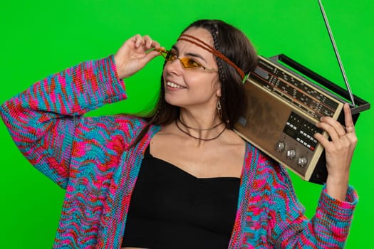 Woman in sunglasses using retro tape record player to listen music, disco dancing of favorite track, having fun, entertaining, fan of vintage technologies. Girl isolated on green chroma key background