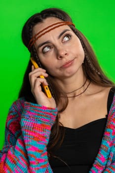 Tired sleepy young woman talking on mobile phone with friend making online conversation. Disinterested hippie girl having annoyed boring talk on smartphone isolated on green chroma key background