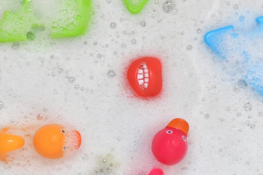 Rubber multicolored toys in a bubble bath for a baby