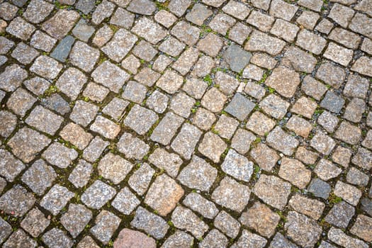 The road is paved with decorative stone. The old road of granite paving stones.