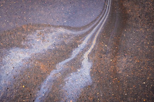 Rainbow gasoline oil spill on the pavement as a texture or background.