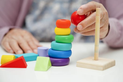 Asian elderly woman playing puzzles game to practice brain training for dementia prevention, Alzheimer disease.
