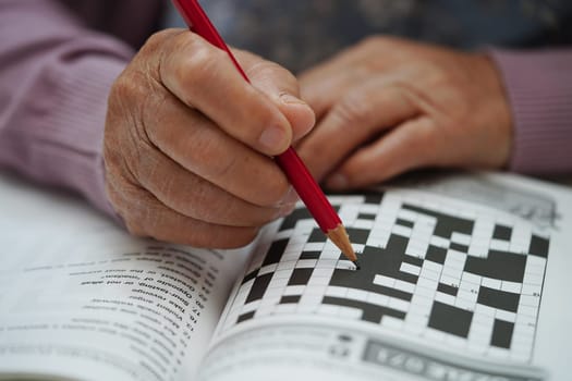 Asian elderly woman playing sudoku puzzle game to practice brain training for dementia prevention, Alzheimer disease.