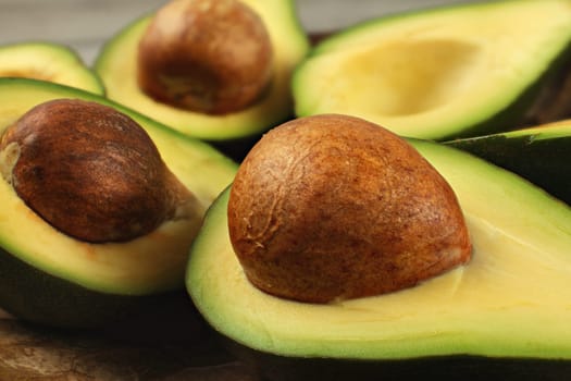 Avocado fruits cut in half, seed visible, close up photo, showing structure on brown pit.