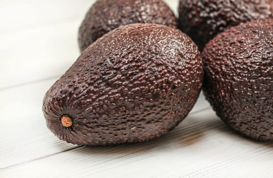 Dark brown ripe avocados on white boards. Close up, detail on skin texture visible.
