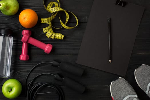 Athlete's set with female clothing, sneakers and bottle of water on dark background. Top view. Copy space. Still life. Ideal for sporty blog.