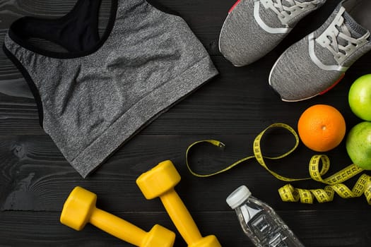 Workout plan with fitness food and sport equipment on dark background, top view. Copy space. Still life