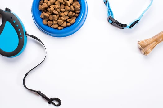 Collar, blue bowl with feed, leash and delicacy for dogs. Isolated on white background. Top view. Still life. Copy space