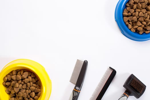dry pet food in bowl, combs and brushes for dogs on white background top view. Still life. Copy space