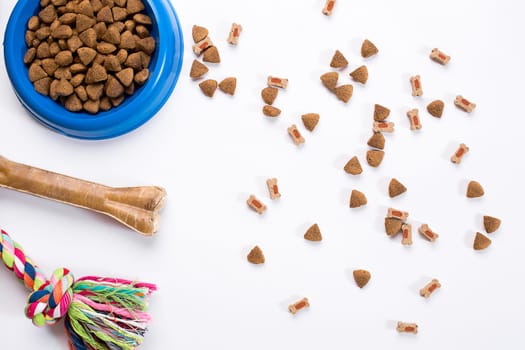 dry pet food in bowl and toys for dogs on white background top view. Still life. Copy space
