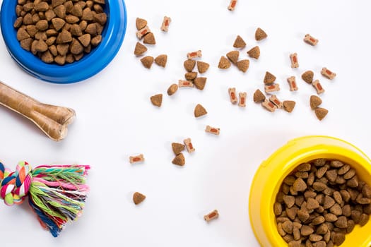 dry pet food in bowl and toys for dogs on white background top view. Still life. Copy space