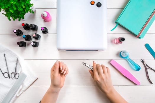 woman hands making manicure to herself on wooden background. Top view. Copy space. Nail Care.