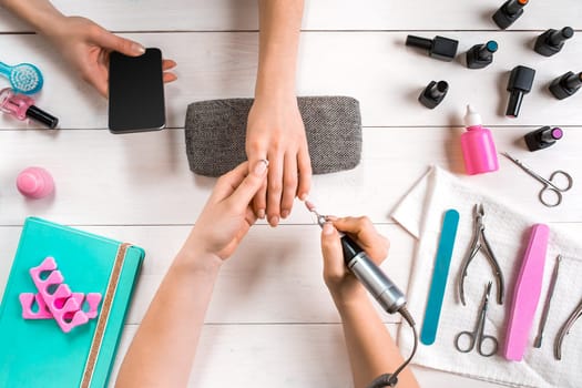 Manicure for the client. Close-up of the hands of a manicurist and client on a wooden background. Nail care. Manicure set and nail polish.