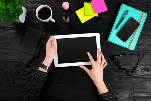 Hand use tablet on desk table top view. Copy space. Flat lay. Black background
