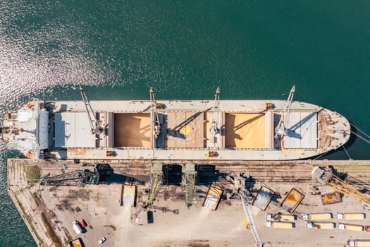 Aerial Top down view Black Sea port Loading of dry cargo ship with ukranian grain by cranes. Maritime grain Import and export concept