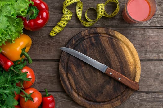Sport and diet. Vegetables, a glass of tomato juice and centimeter. Peppers, tomatoes, salad on rustic background. Top view. Copy space