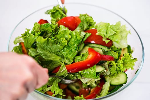 Healthy eating, vegetarian food, dieting and people concept - close up of young woman dressing vegetable salad with olive oil on a white background