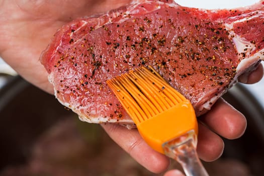 Close up of chefs hands spicing the meat. Casserole with raw meat on a white background.
