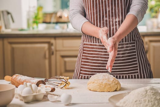 Woman slap his hands above dough closeup. Baker finishing his bakery, shake flour from his hands, free space for text. Homemade bakery, cooking process concept
