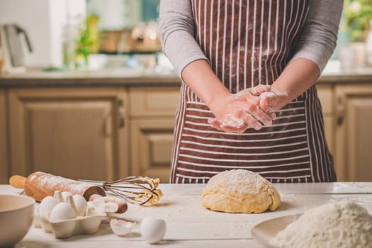 Woman slap his hands above dough closeup. Baker finishing his bakery, shake flour from his hands, free space for text. Homemade bakery, cooking process concept