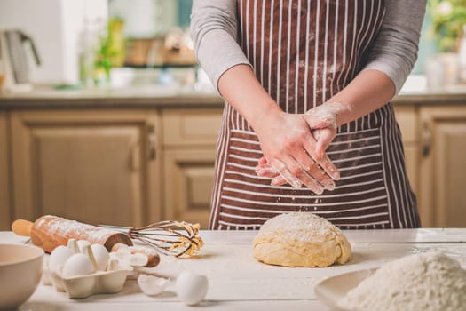Woman slap his hands above dough closeup. Baker finishing his bakery, shake flour from his hands, free space for text. Homemade bakery, cooking process concept