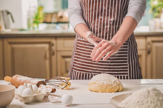 Woman slap his hands above dough closeup. Baker finishing his bakery, shake flour from his hands, free space for text. Homemade bakery, cooking process concept