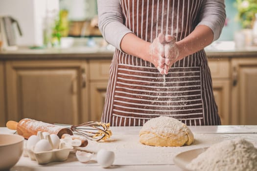 Woman slap his hands above dough closeup. Baker finishing his bakery, shake flour from his hands, free space for text. Homemade bakery, cooking process concept