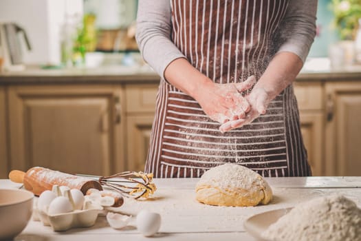 Woman slap his hands above dough closeup. Baker finishing his bakery, shake flour from his hands, free space for text. Homemade bakery, cooking process concept